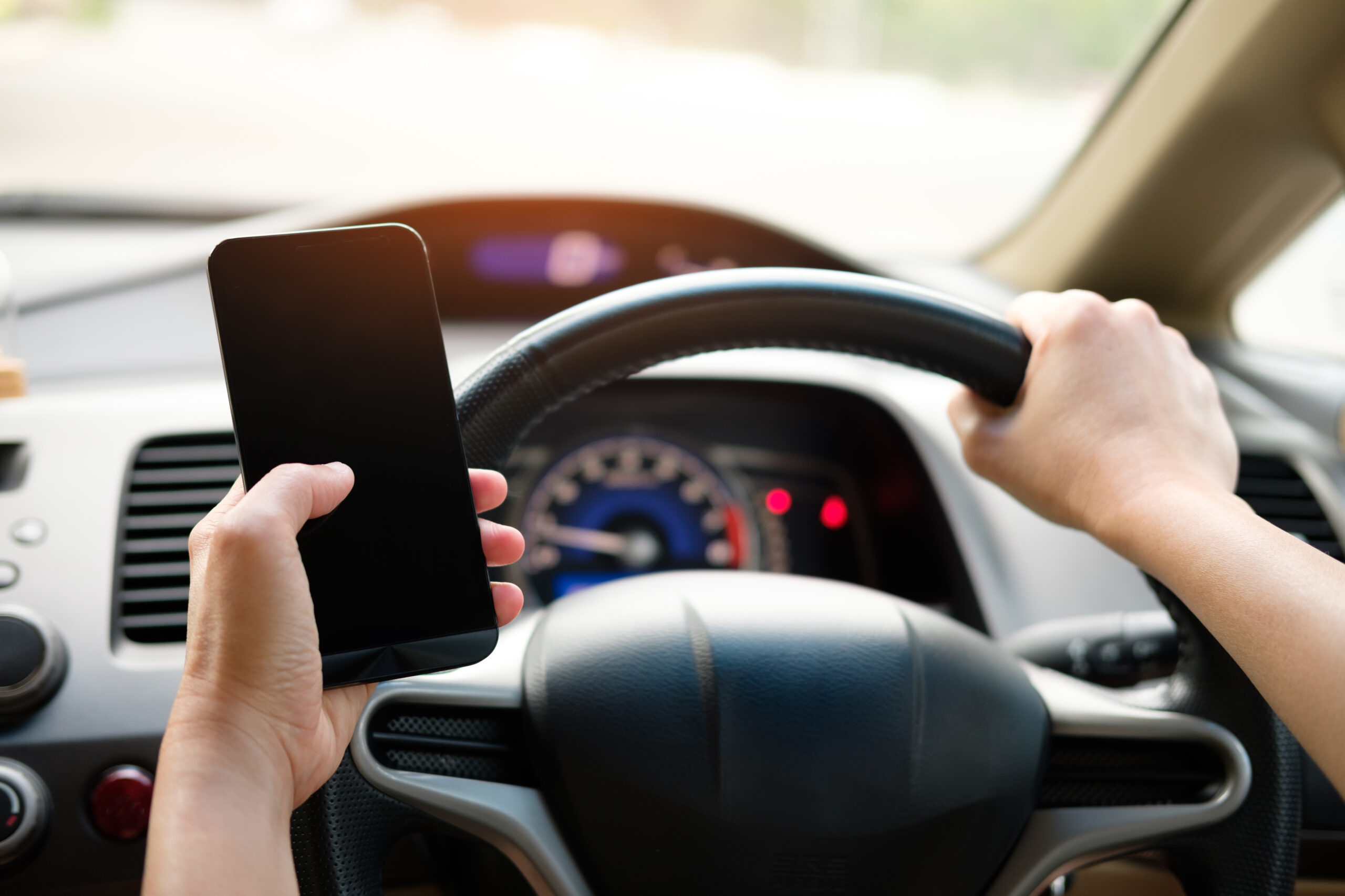 Hand is holding a touch phone in the car.